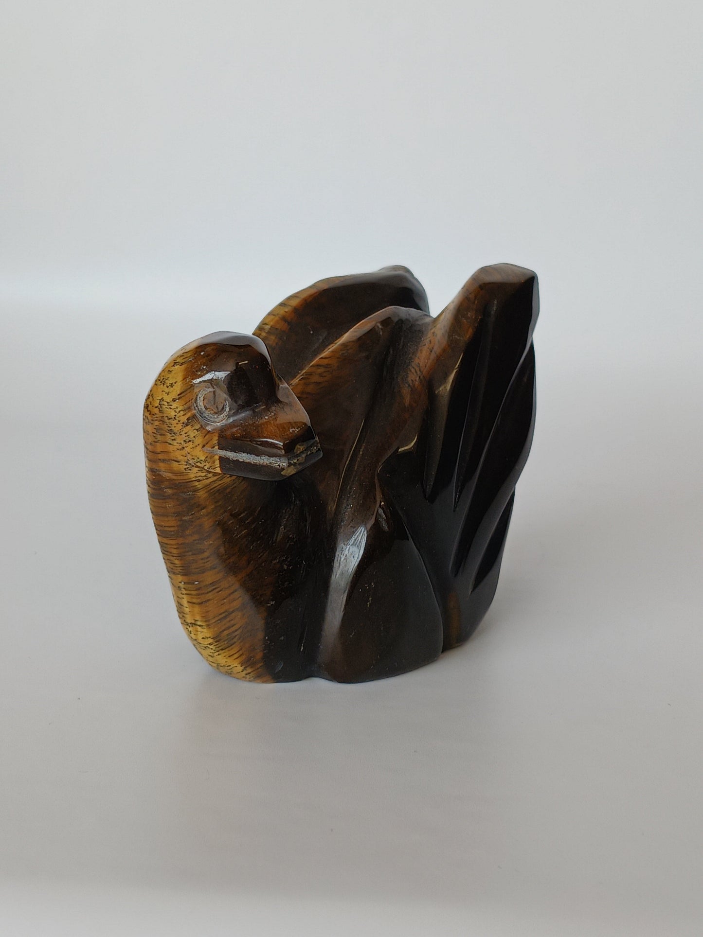 Assorted hand-carved animal figurines made from Blue Tiger’s Eye, Fluorite, and Tiger’s Eye crystals, each featuring unique colors and patterns, displayed on a white background.