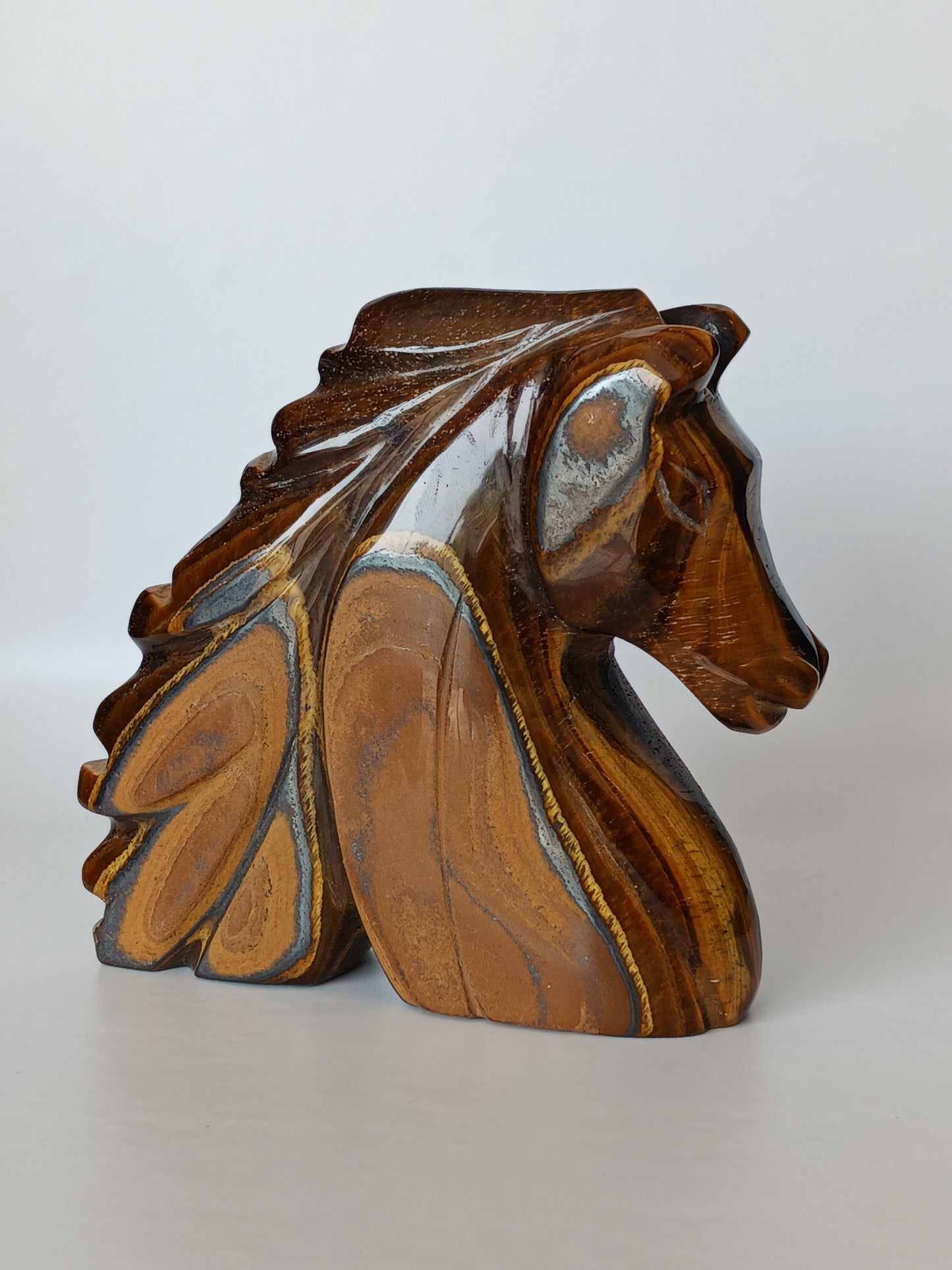 Assorted hand-carved animal figurines made from Blue Tiger’s Eye, Fluorite, and Tiger’s Eye crystals, each featuring unique colors and patterns, displayed on a white background.