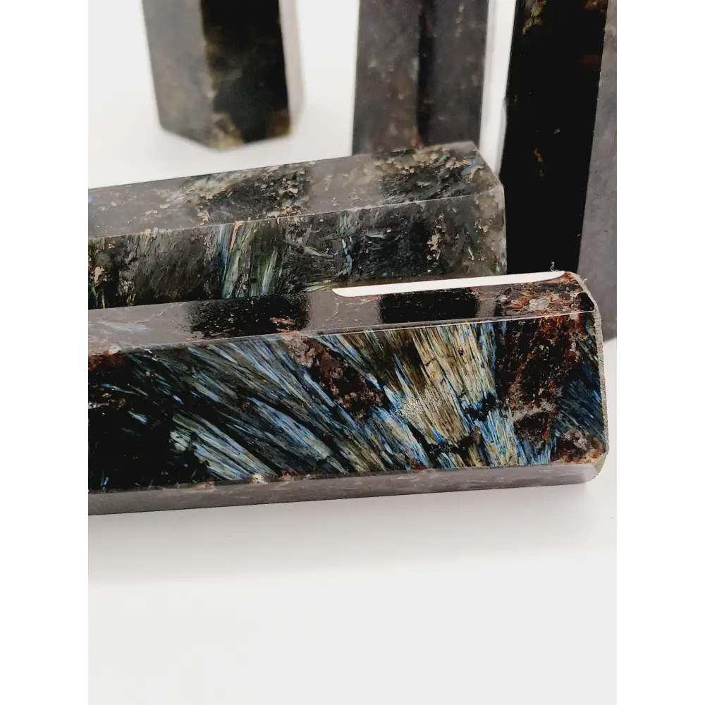 Astrophyllite (firework stone) with garnet tower, 2.5ā3 inches, hand-polished with golden flashes and deep red inclusions, displayed on a white background.
