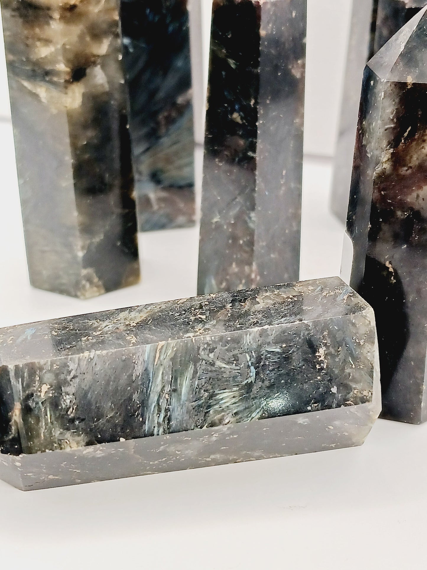 Astrophyllite (firework stone) with garnet tower, 2.5ā3 inches, hand-polished with golden flashes and deep red inclusions, displayed on a white background.
