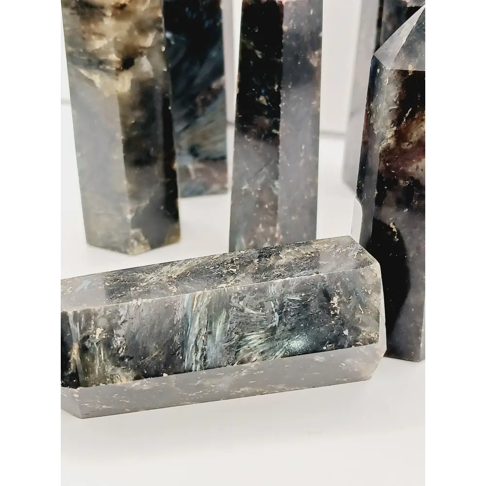 Astrophyllite (firework stone) with garnet tower, 2.5ā3 inches, hand-polished with golden flashes and deep red inclusions, displayed on a white background.
