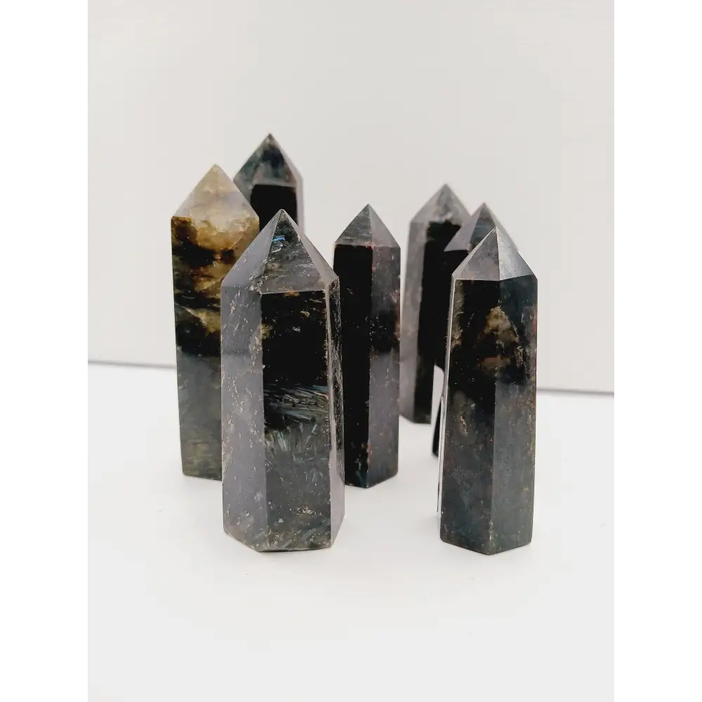 Astrophyllite (firework stone) with garnet tower, 2.5ā3 inches, hand-polished with golden flashes and deep red inclusions, displayed on a white background.