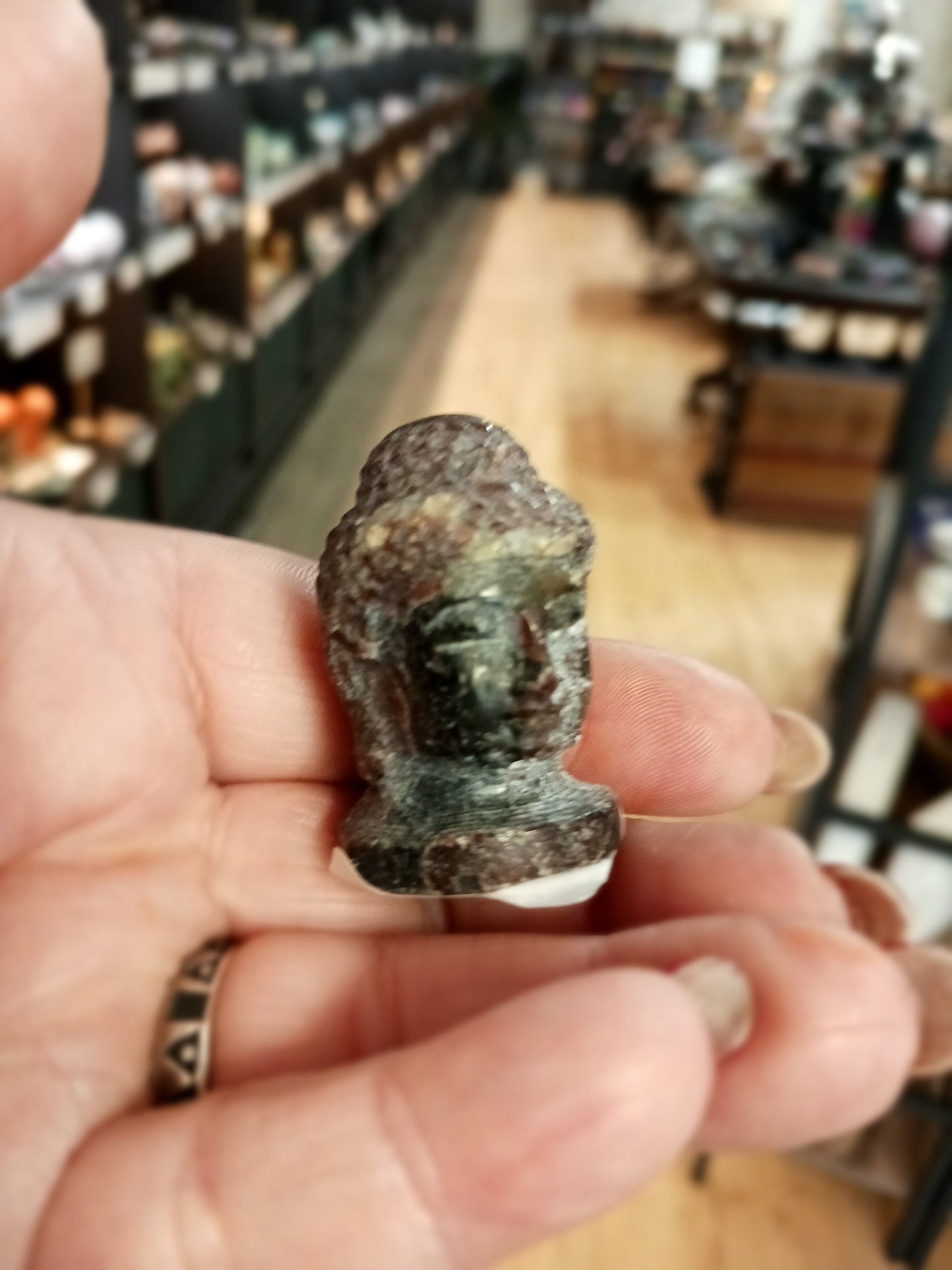 Hand-carved 1 1/2 inch tall Buddha head figurines in assorted crystal materials such as amethyst, rose quartz, clear quartz, and jade, displayed on a white background.