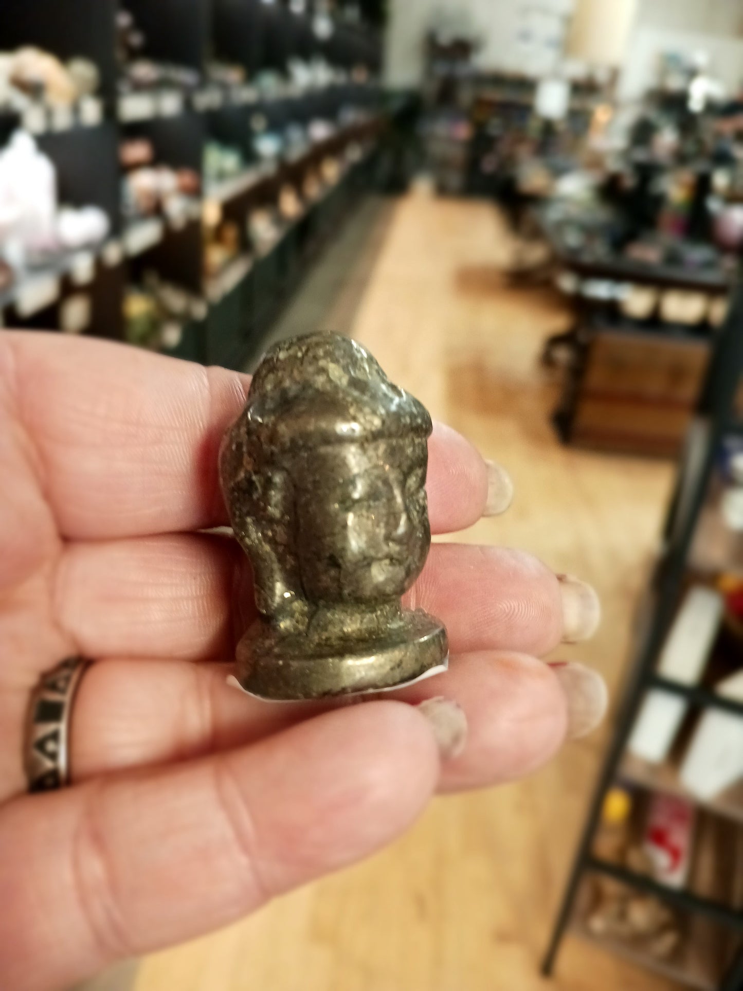 Hand-carved 1 1/2 inch tall Buddha head figurines in assorted crystal materials such as amethyst, rose quartz, clear quartz, and jade, displayed on a white background.