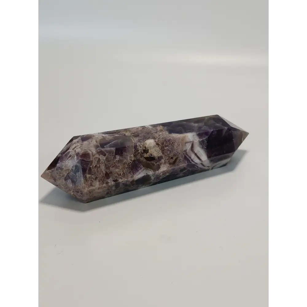 Double terminated Dream Amethyst crystal featuring bold purple and white chevron patterns, displayed on a white background.