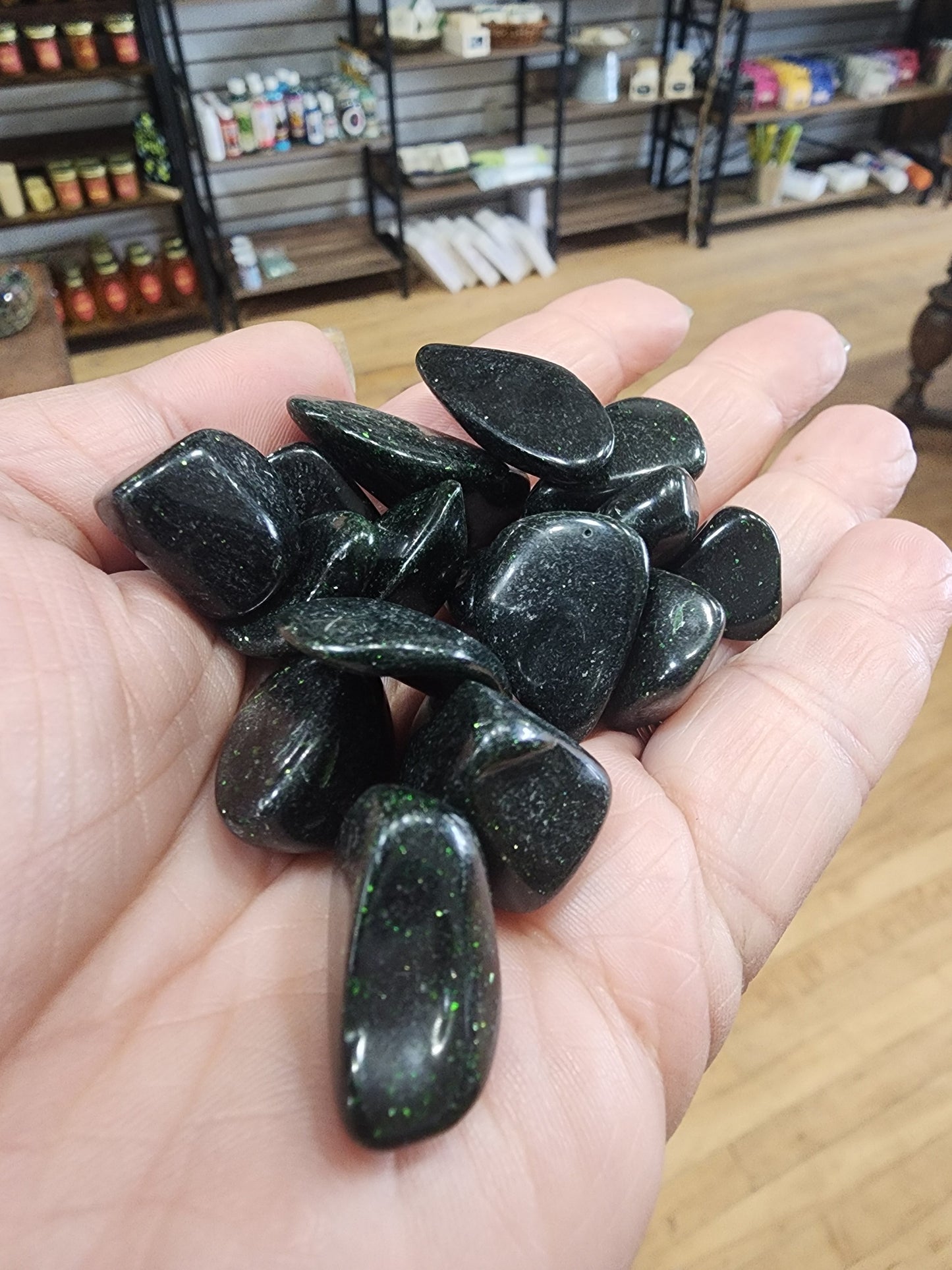 Polished green goldstone tumble with a sparkling, glittery surface, displayed on a white background. Perfect for ambition, abundance, and heart chakra energy.