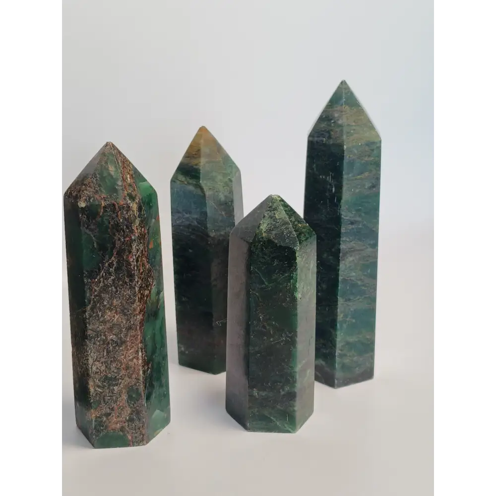 Hand-polished Green Zoisite stone featuring vibrant green hues, sometimes with black or ruby inclusions, displayed on a white background.