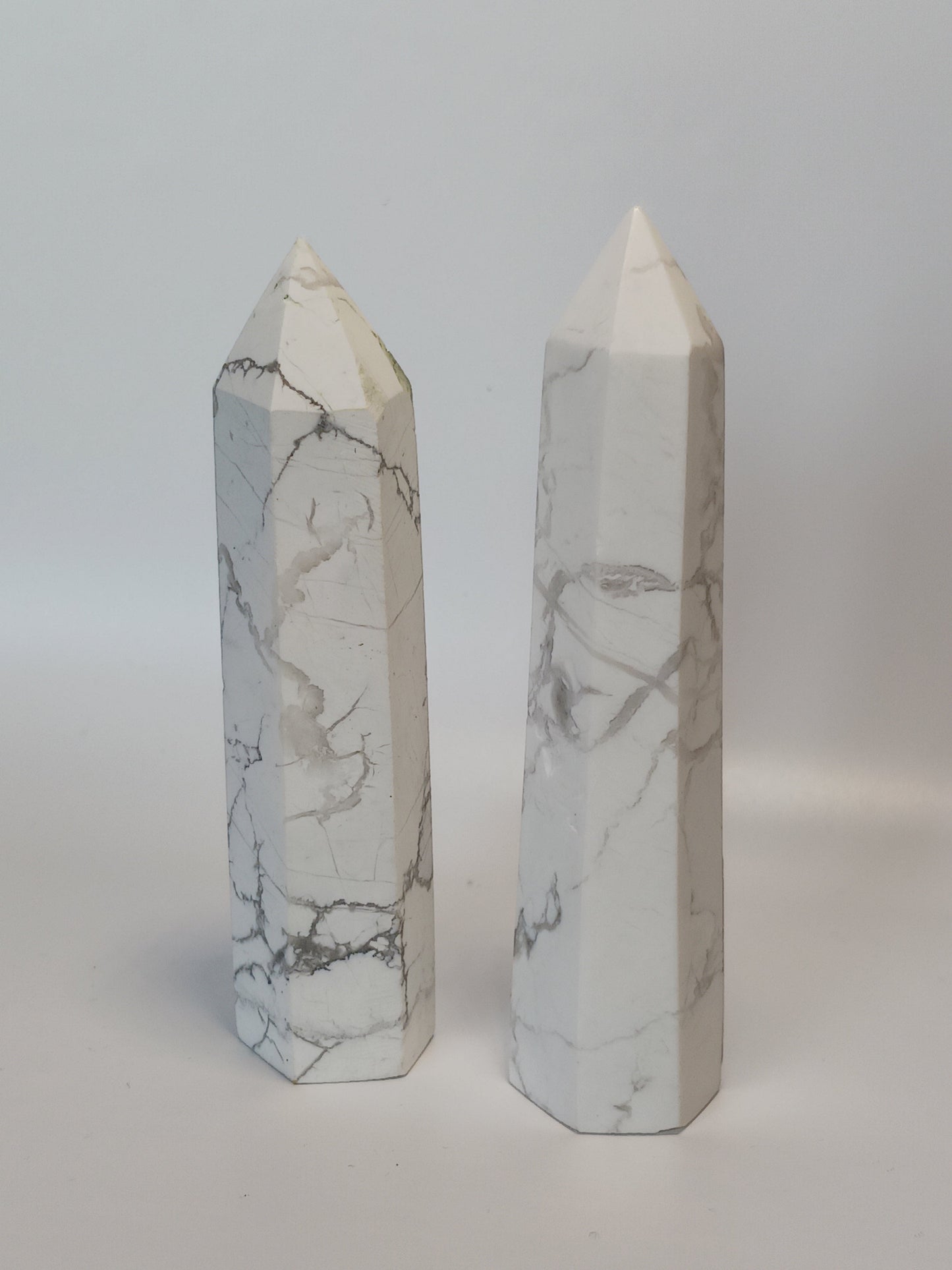 Hand-carved Howlite point featuring soft white coloring with graceful gray veining, displayed on a white background.
