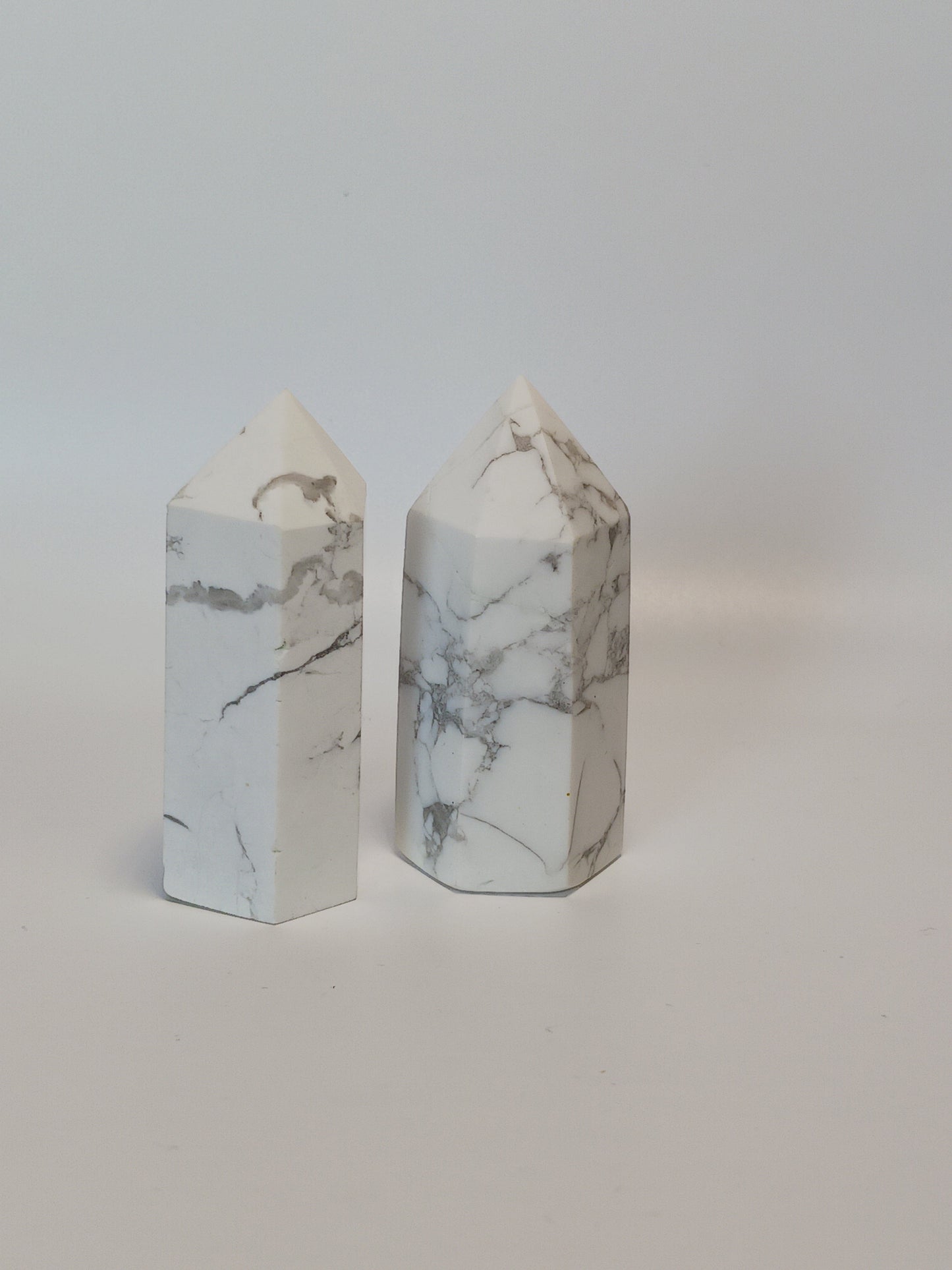 Hand-carved Howlite point featuring soft white coloring with graceful gray veining, displayed on a white background.