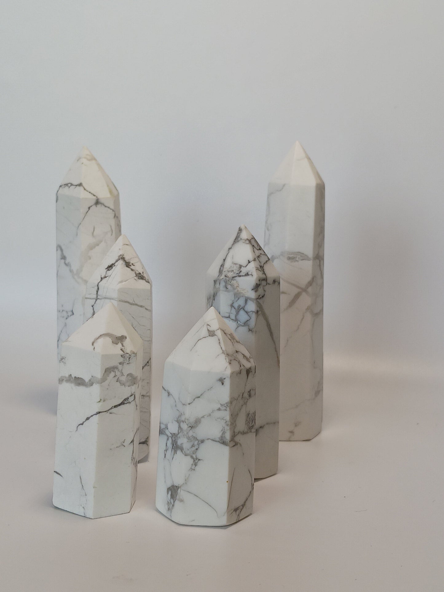 Hand-carved Howlite point featuring soft white coloring with graceful gray veining, displayed on a white background.