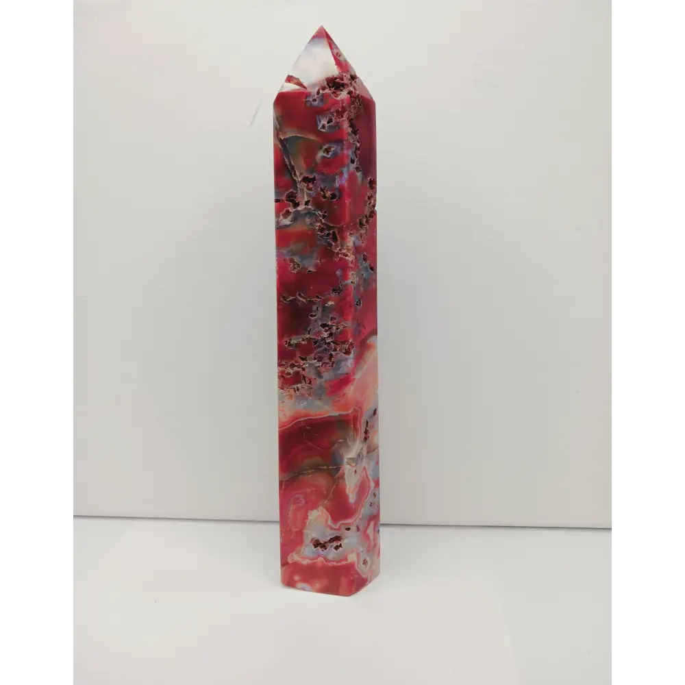 Polished red and white crystal wand on a white background
