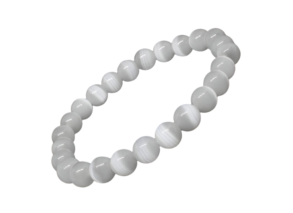 A white selenite bracelet with round beads laid out on a black surface.