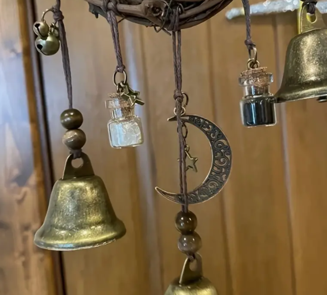Decorative hanging bells with a moon and star design against a blurred background