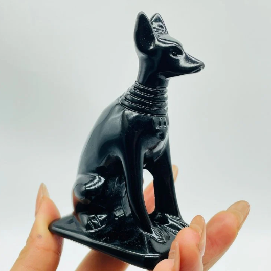 Hand-carved 4-inch Anubis crystal statue featuring a jackal-headed figure with intricate details, made from genuine crystal and displayed on a white background.

