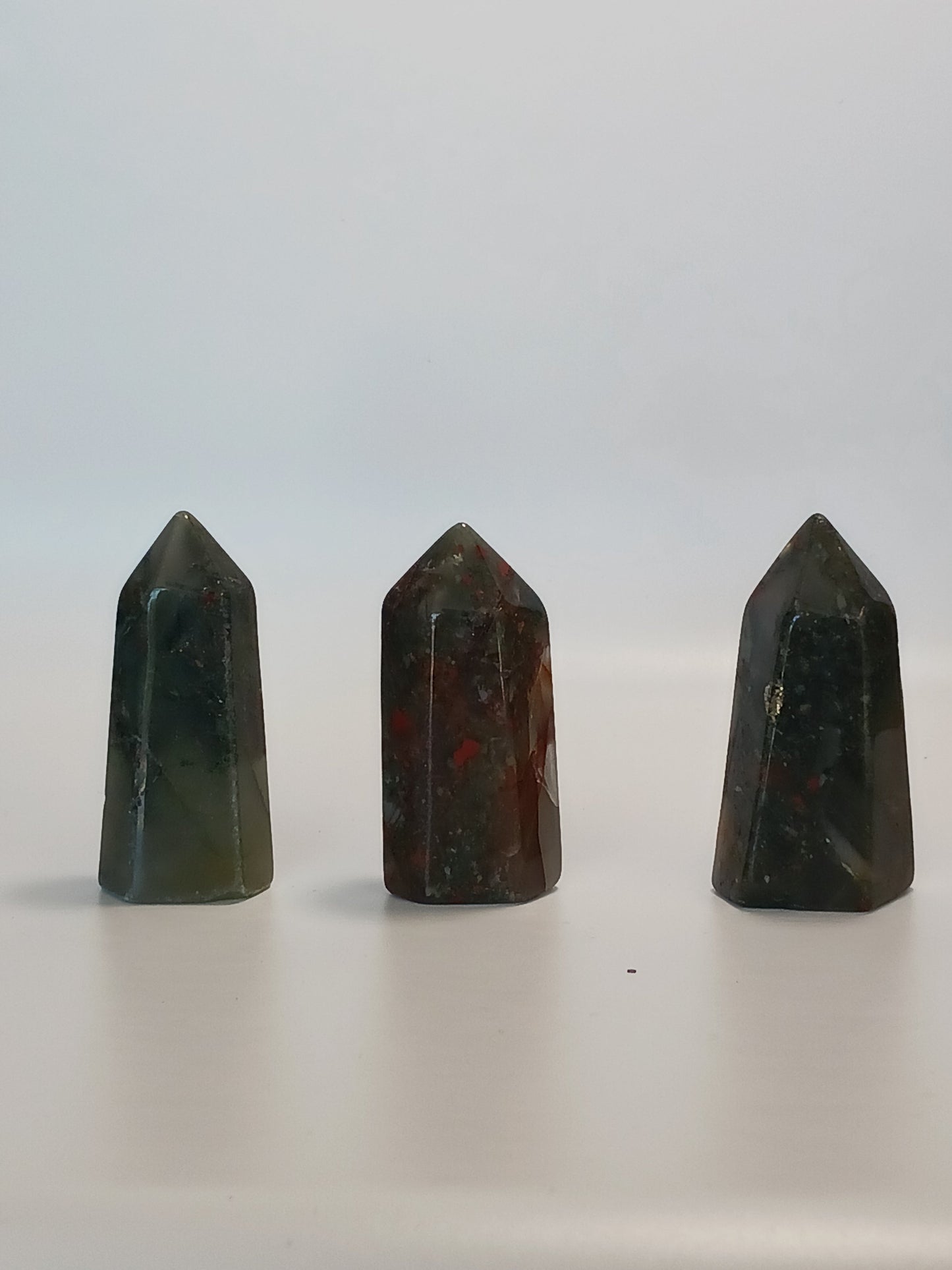 Hand-carved Bloodstone point, 2 to 2.5 inches tall, featuring deep green with natural red flecks, displayed on a white background.