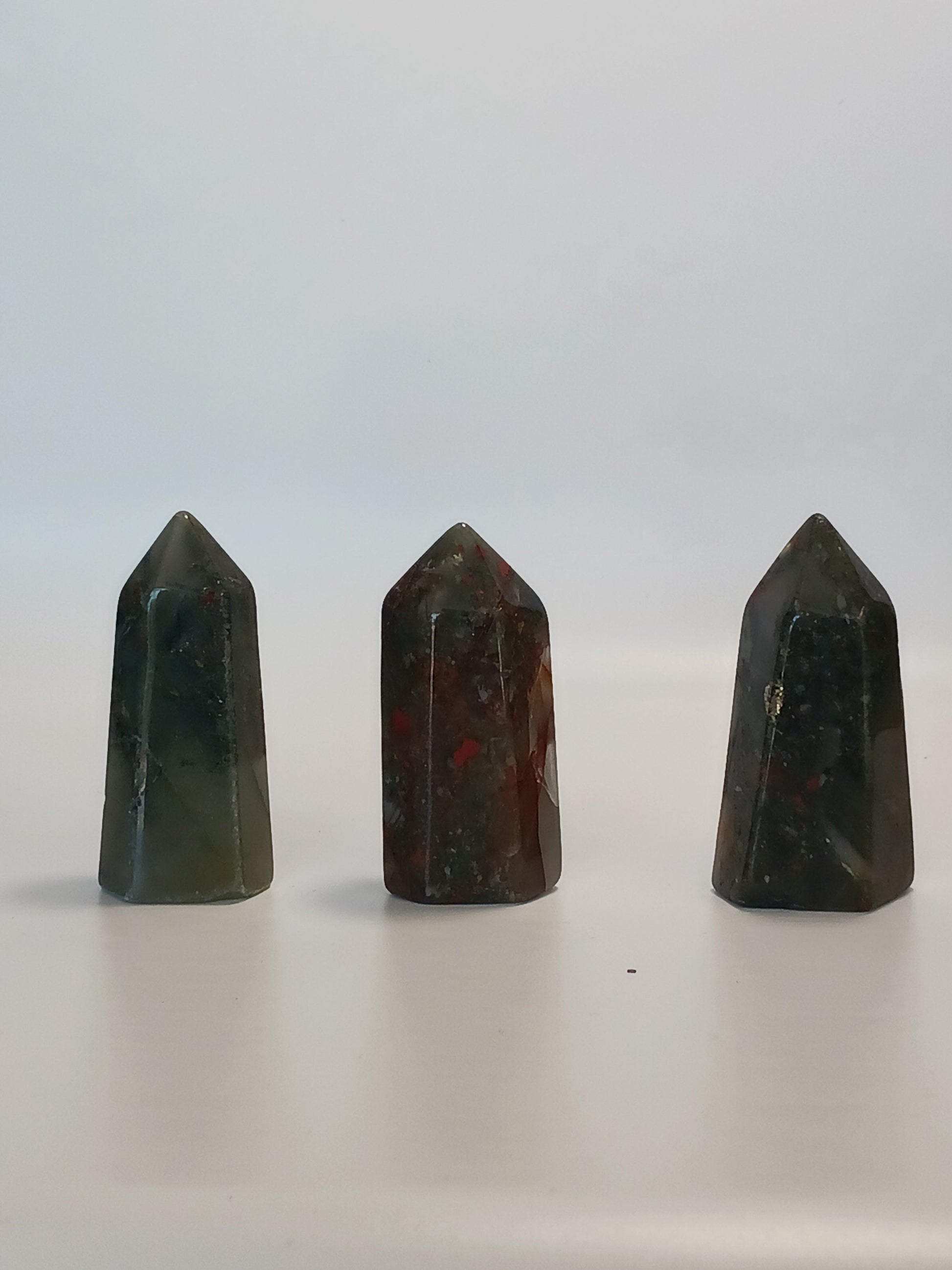 Hand-carved Bloodstone point, 2 to 2.5 inches tall, featuring deep green with natural red flecks, displayed on a white background.