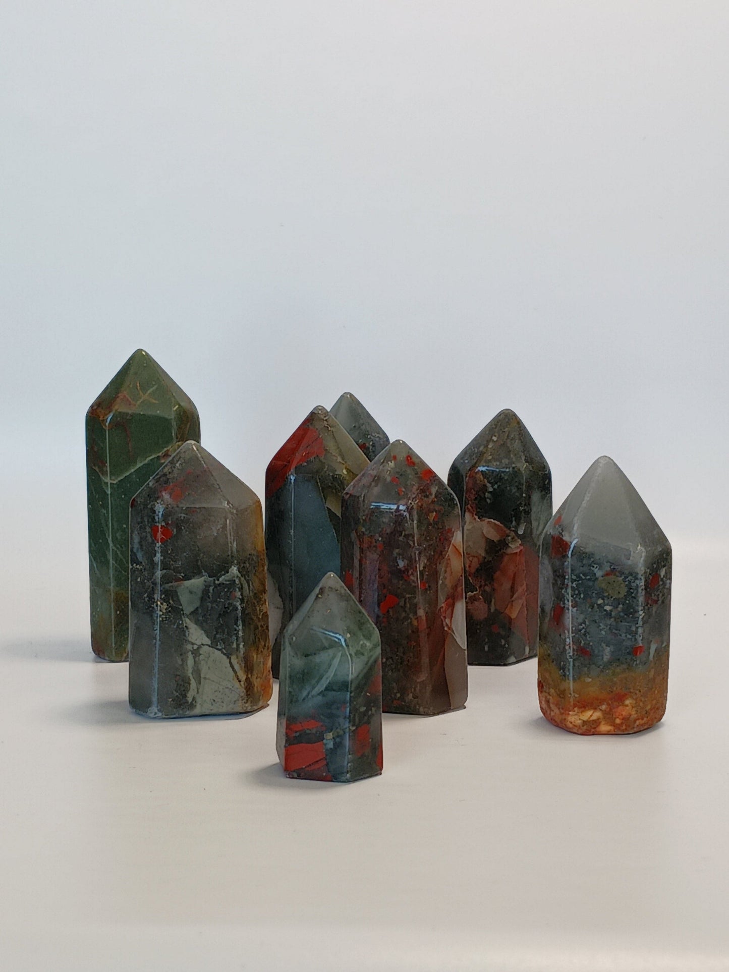 Hand-carved Bloodstone point, 2 to 2.5 inches tall, featuring deep green with natural red flecks, displayed on a white background.
