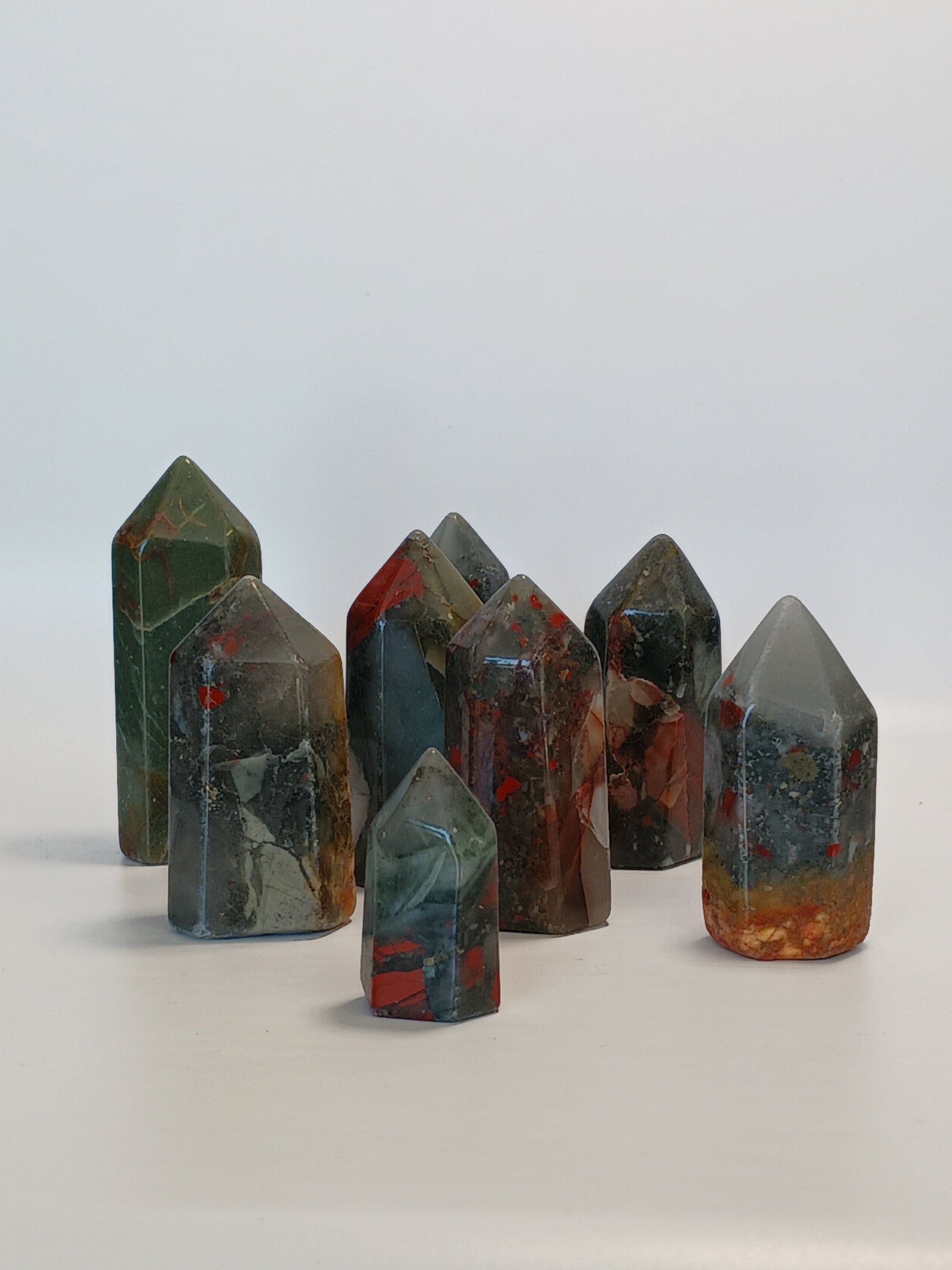 Hand-carved Bloodstone point, 2 to 2.5 inches tall, featuring deep green with natural red flecks, displayed on a white background.