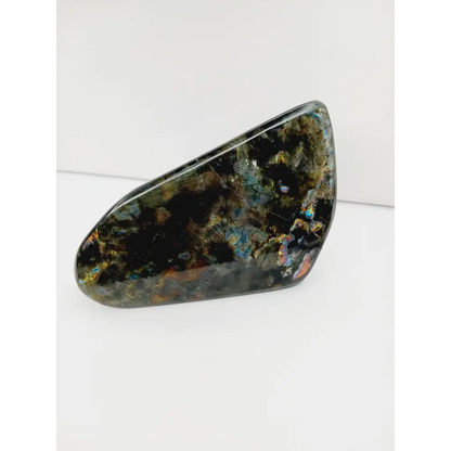 Labradorite freeform with vibrant flashes of blue, green, and gold, polished and displayed on a white background.