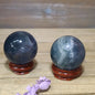 Hand-polished Blue Rose Quartz sphere, 1.5 to 1.75 inches in diameter, featuring soothing blue and soft pink hues, displayed on a white background.