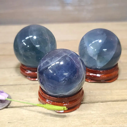Hand-polished Blue Rose Quartz sphere, 1.5 to 1.75 inches in diameter, featuring soothing blue and soft pink hues, displayed on a white background.
