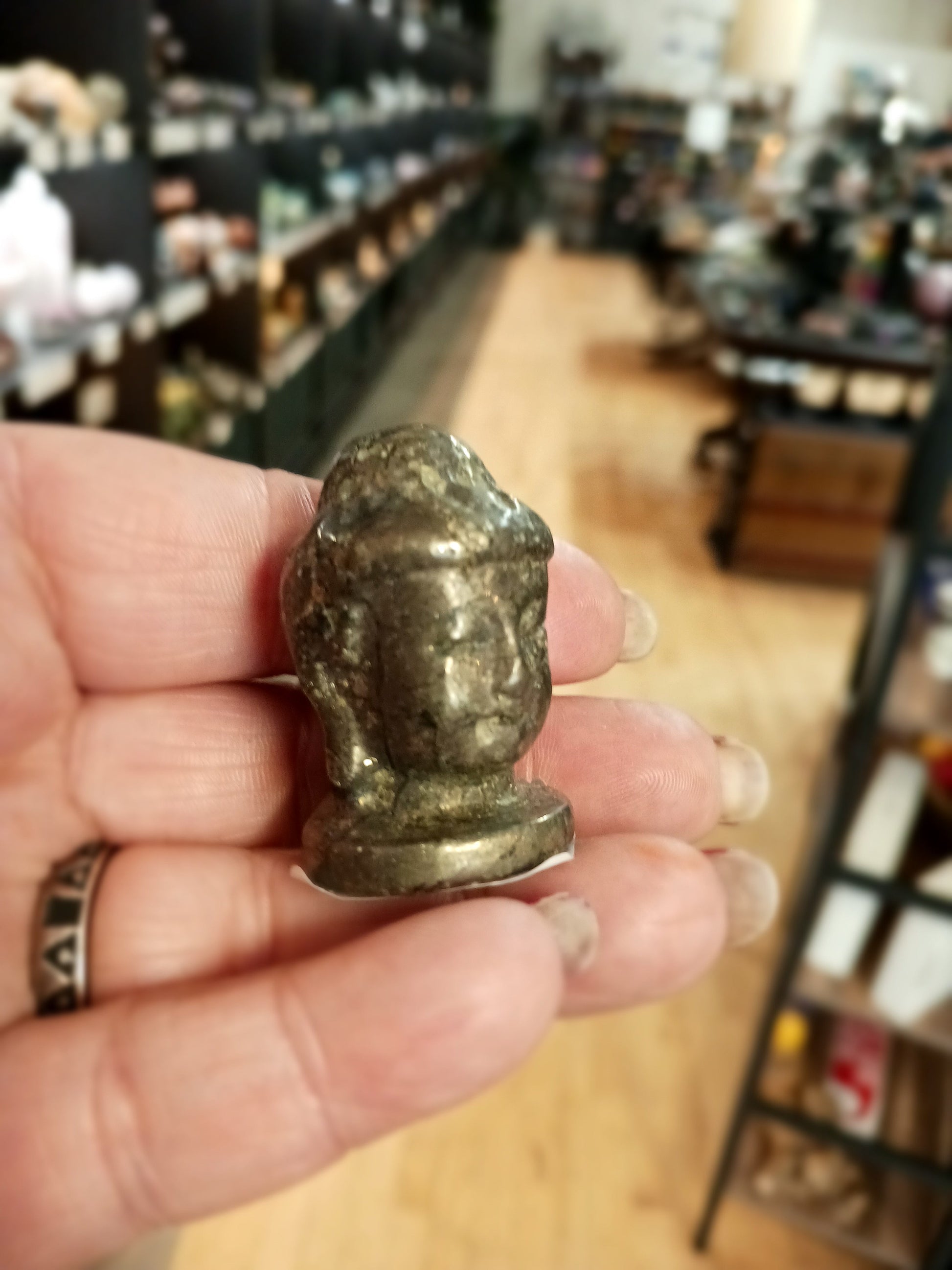 Hand-carved 1 1/2 inch tall Buddha head figurines in assorted crystal materials such as amethyst, rose quartz, clear quartz, and jade, displayed on a white background.