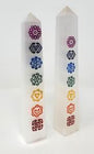 Hand-carved selenite obelisk with vibrant chakra stones arranged vertically, displayed on a white background. Perfect for cleansing, chakra alignment, and high-vibrational energy.