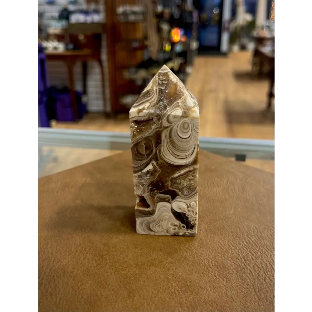 Hand-carved Mexican Crazy Lace Agate tower featuring intricate, colorful swirls and banded patterns, displayed on a white background.