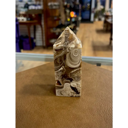 Hand-carved Mexican Crazy Lace Agate tower featuring intricate, colorful swirls and banded patterns, displayed on a white background.
