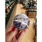 Hand-polished Dream Amethyst sphere featuring vivid purple and white chevron bands, displayed on a white background.