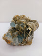 Muscovite with aquamarine specimen, showcasing shimmering layers and blue crystal accents, displayed on a white background.