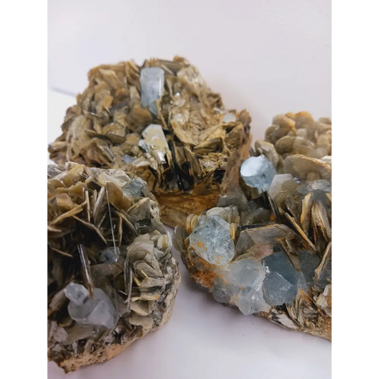 Muscovite with aquamarine specimen, showcasing shimmering layers and blue crystal accents, displayed on a white background.