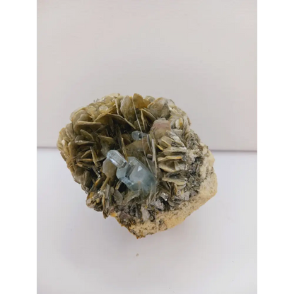 Muscovite with aquamarine specimen, showcasing shimmering layers and blue crystal accents, displayed on a white background.