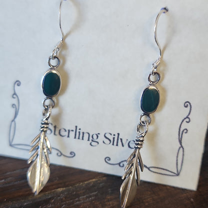 Sterling silver feather earrings featuring vibrant malachite stones, displayed on a white background. Perfect for transformation, protection, and spiritual freedom.