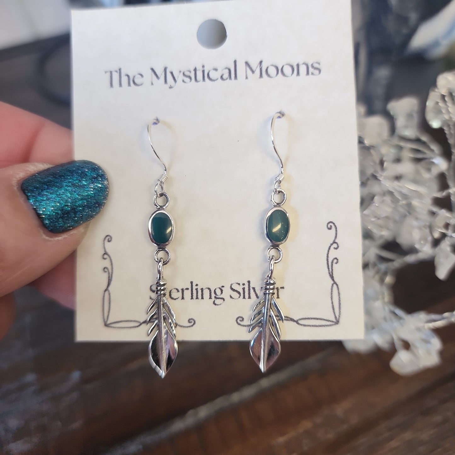 Sterling silver feather earrings featuring vibrant malachite stones, displayed on a white background. Perfect for transformation, protection, and spiritual freedom.