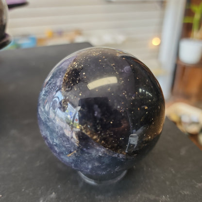 Hand-polished Fluorite with Pyrite sphere featuring vibrant green, purple, or blue fluorite hues with sparkling pyrite inclusions, displayed on a white background.
