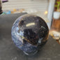 Hand-polished Fluorite with Pyrite sphere featuring vibrant green, purple, or blue fluorite hues with sparkling pyrite inclusions, displayed on a white background.