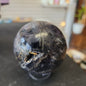Hand-polished Fluorite with Pyrite sphere featuring vibrant green, purple, or blue fluorite hues with sparkling pyrite inclusions, displayed on a white background.