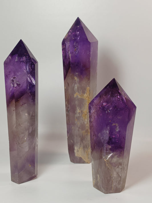 Polished freestanding Amethyst wand with deep purple hues and natural clarity, displayed on a white background.