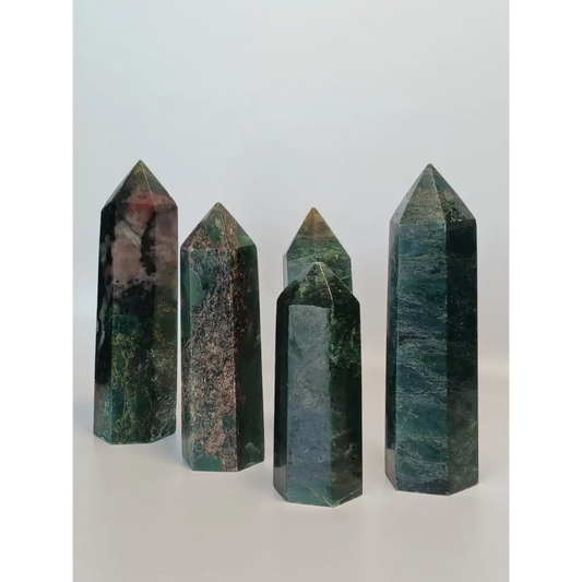 Hand-polished Green Zoisite stone featuring vibrant green hues, sometimes with black or ruby inclusions, displayed on a white background.