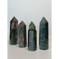 Hand-polished Green Zoisite stone featuring vibrant green hues, sometimes with black or ruby inclusions, displayed on a white background.