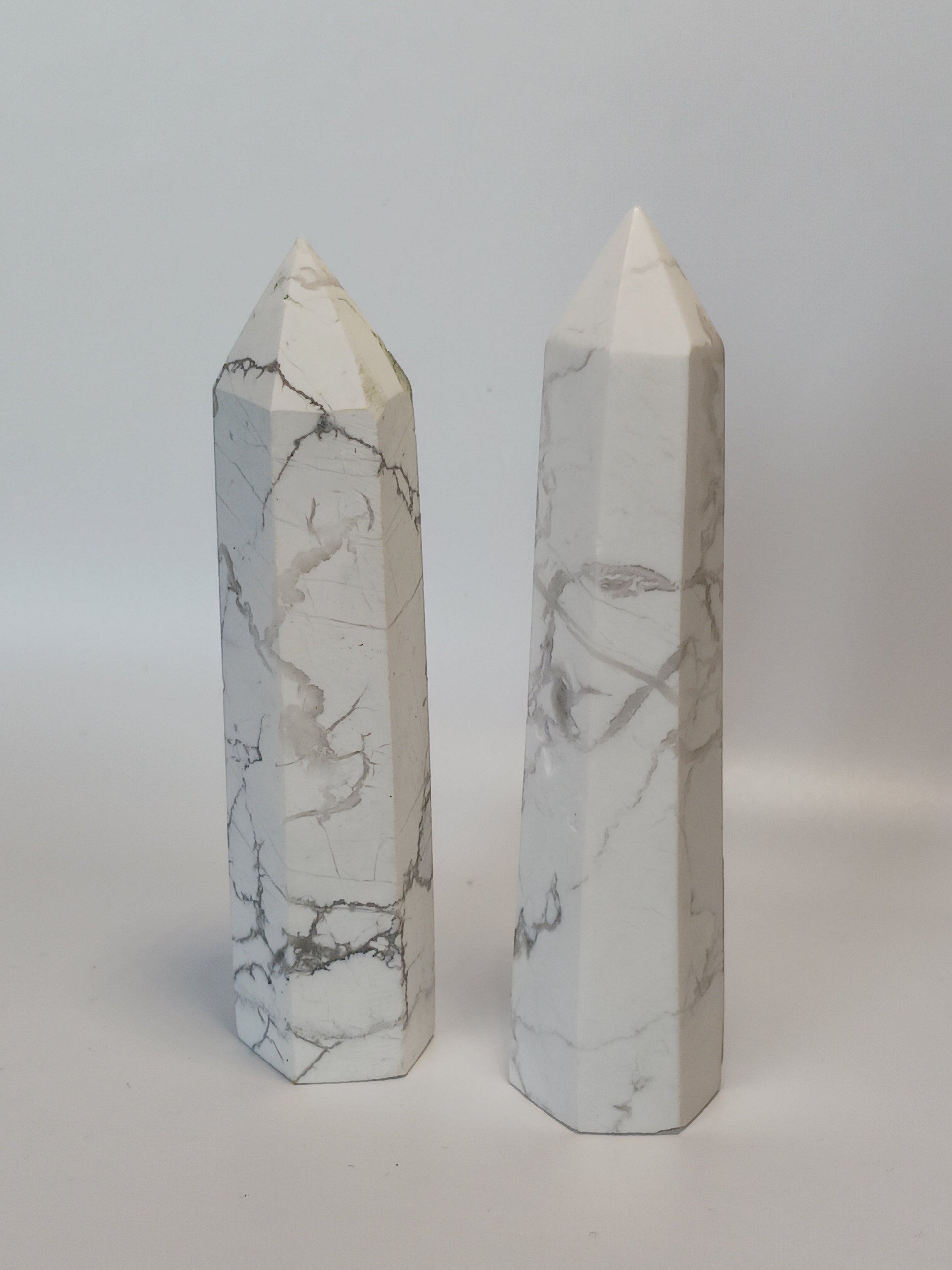 Hand-carved Howlite point featuring soft white coloring with graceful gray veining, displayed on a white background.