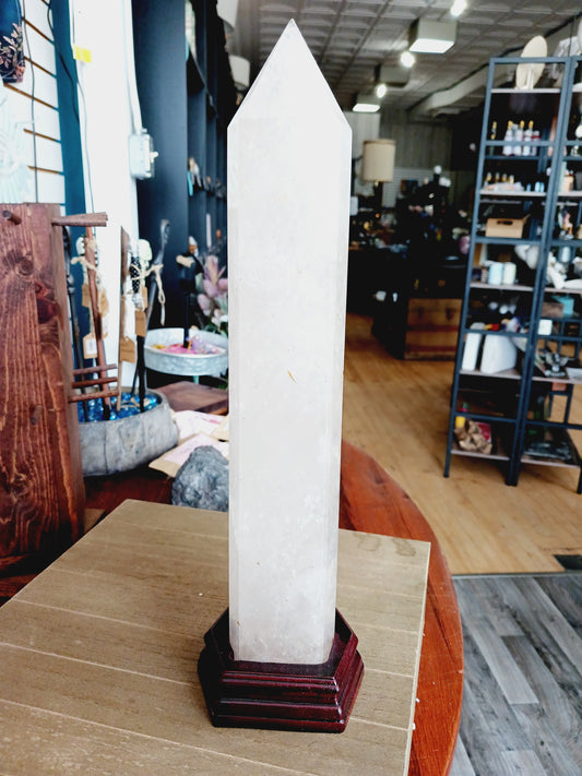 Huge clear quartz tower, polished and mounted on a sturdy stand, with brilliant clarity and natural inclusions, displayed on a white background.