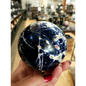 Hand-polished Sodalite sphere featuring deep blue hues with natural white marbling, displayed on a white background.