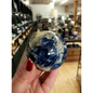 Hand-polished Sodalite sphere featuring deep blue hues with natural white marbling, displayed on a white background.