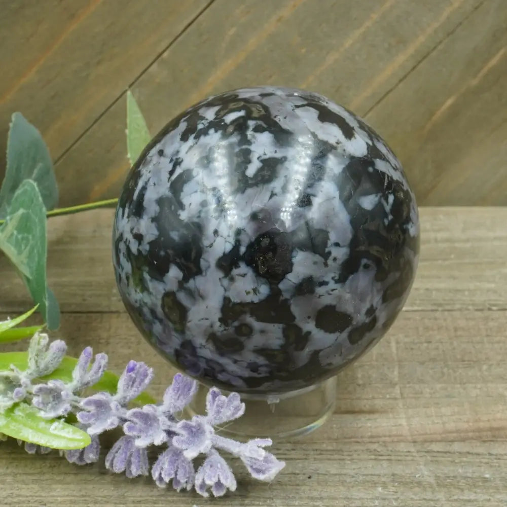Hand-polished Indigo Gabbro sphere featuring swirling indigo, black, and gray patterns, displayed on a white background.