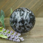 Hand-polished Indigo Gabbro sphere featuring swirling indigo, black, and gray patterns, displayed on a white background.