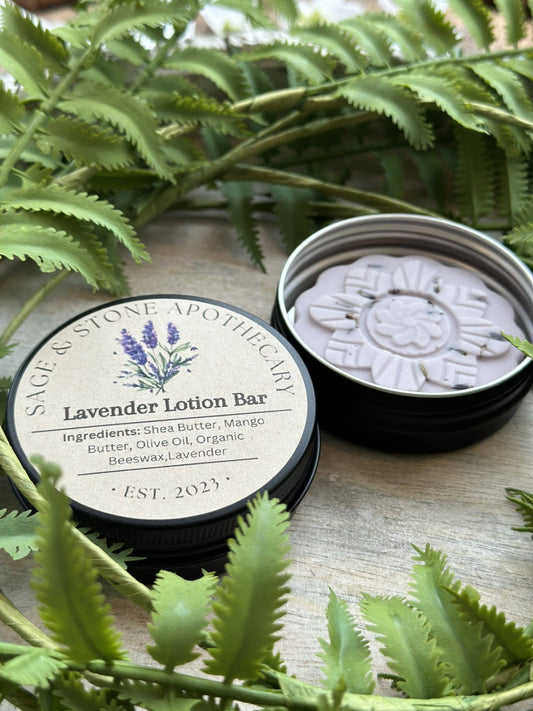 Lavender Lotion Bar in a round shape, surrounded by sprigs of fresh lavender and natural butters, displayed on a white background. Perfect for nourishing, soothing, and hydrating skin.