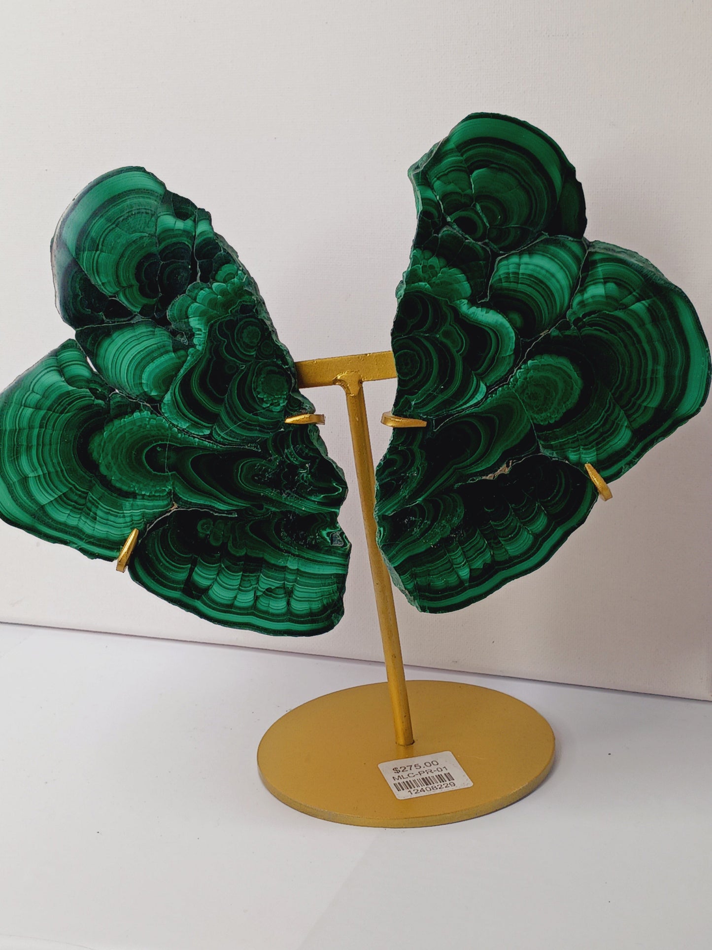 Pair of polished malachite slabs with vibrant green banding, displayed upright on a metal stand against a white background.