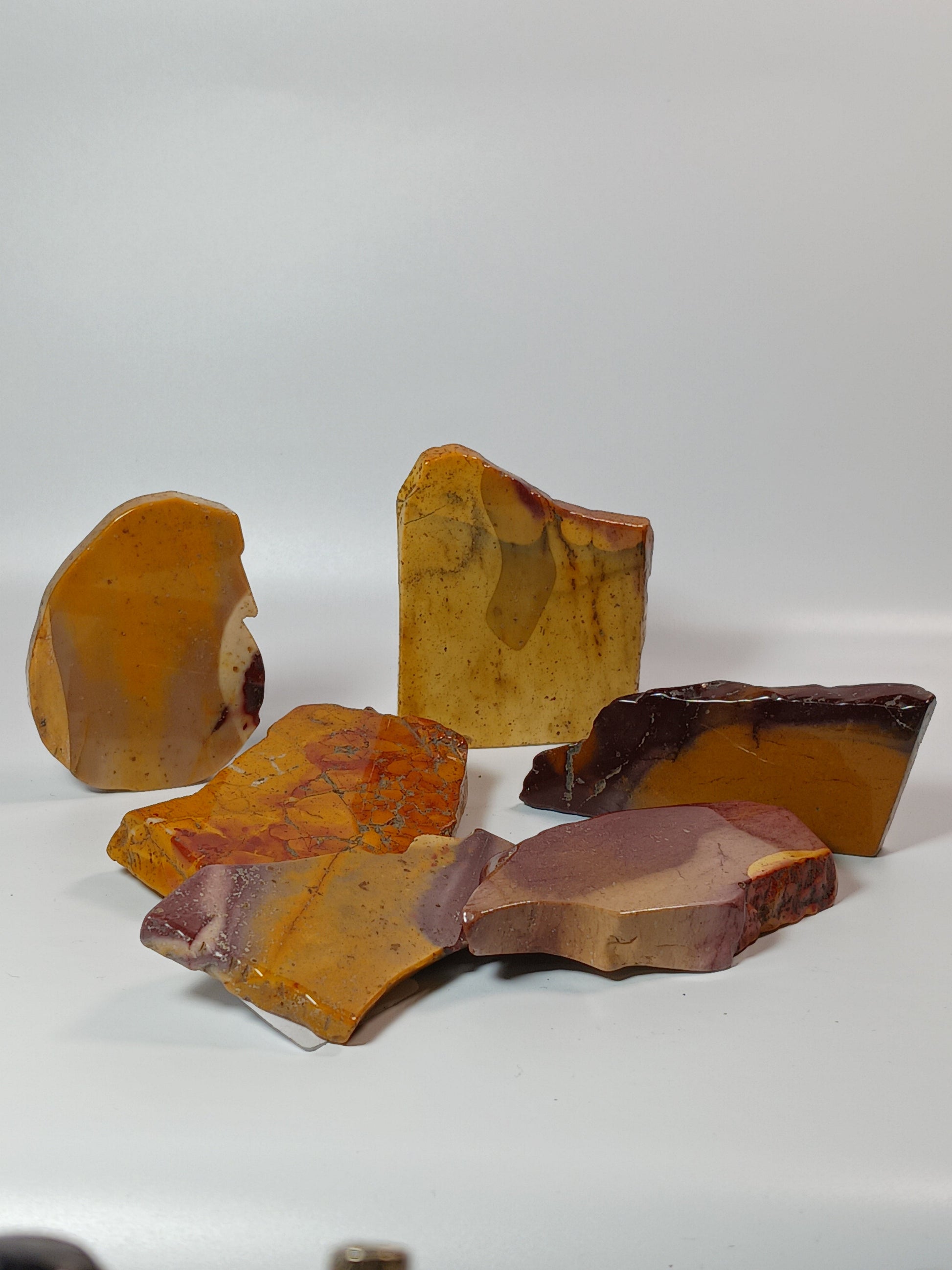 Hand-polished Mookaite slab, 2–2.5 inches, with vibrant red, yellow, and cream patterns, displayed on a white background.